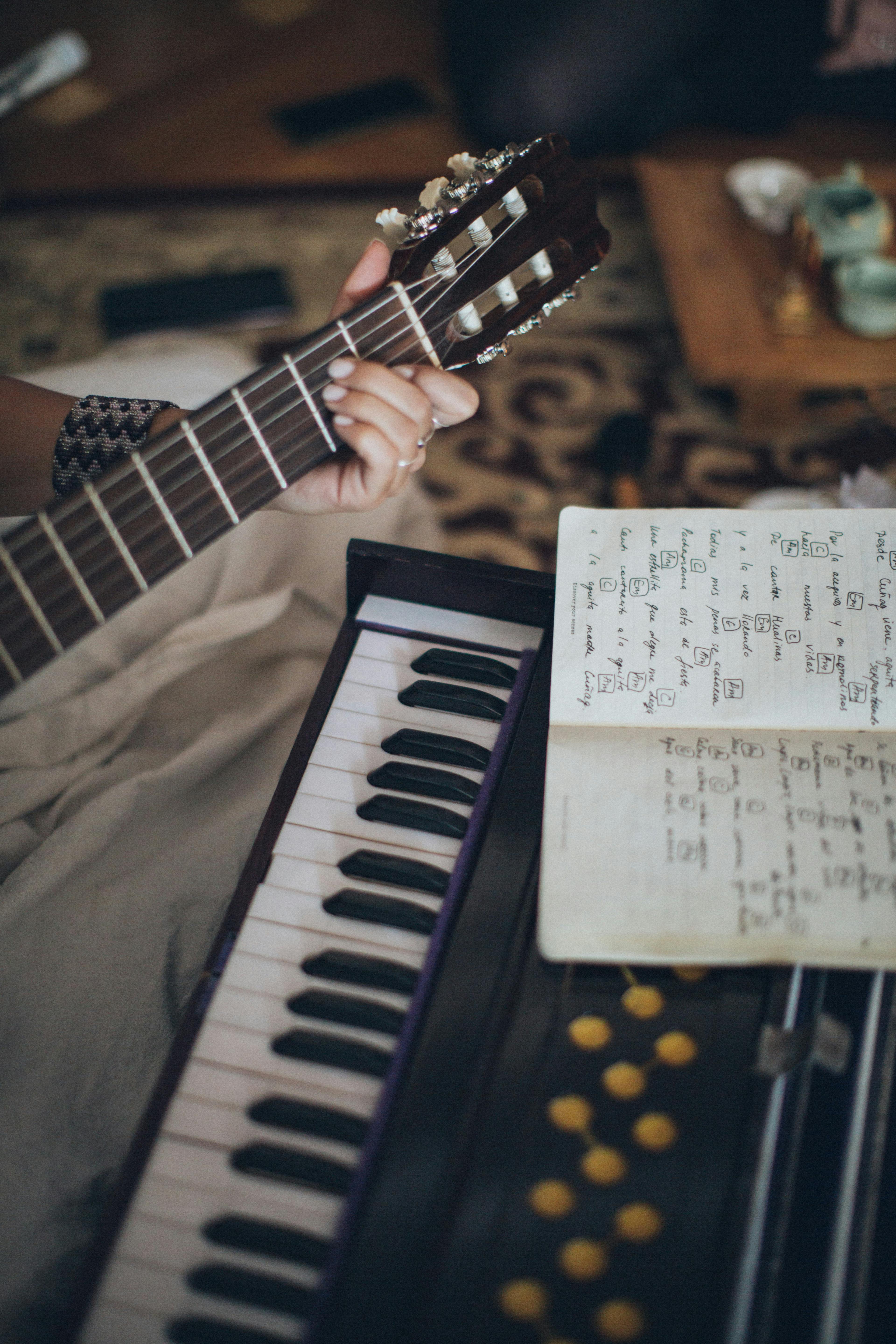 The neck of a guitar, the end of a piano keyboard, and a page of music.